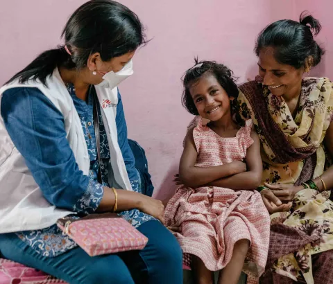 Vaishnavi, 7, who lives with drug-resistant TB, interacts with MSF nurse Prachi, as her mother Vishaka holds her. Mumbai, India, 2022.